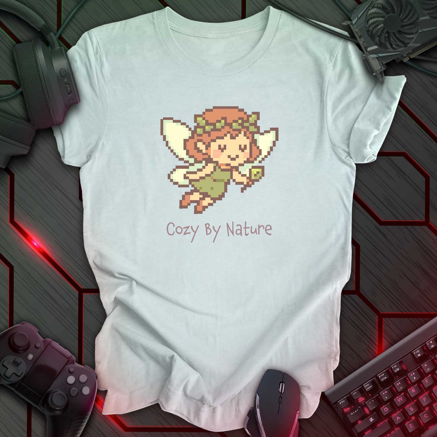 Pixel art fairy with leafy wings and crown holding a wand, smiling above the words "Cozy By Nature" in cozy gamer kawaii style. Heather Ice Blue background.
