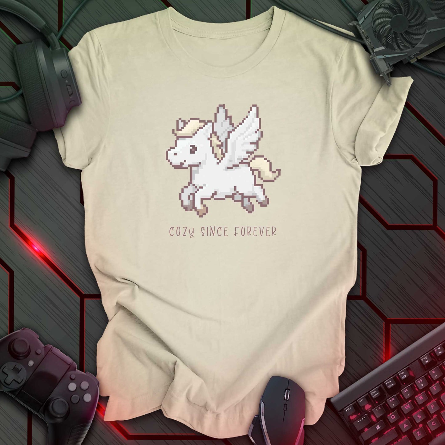 natural color t-shirt with a chest print of a pixel art cute winged Pegasus flying about handwritten styled text that reads "COZY SINCE FOREVER".