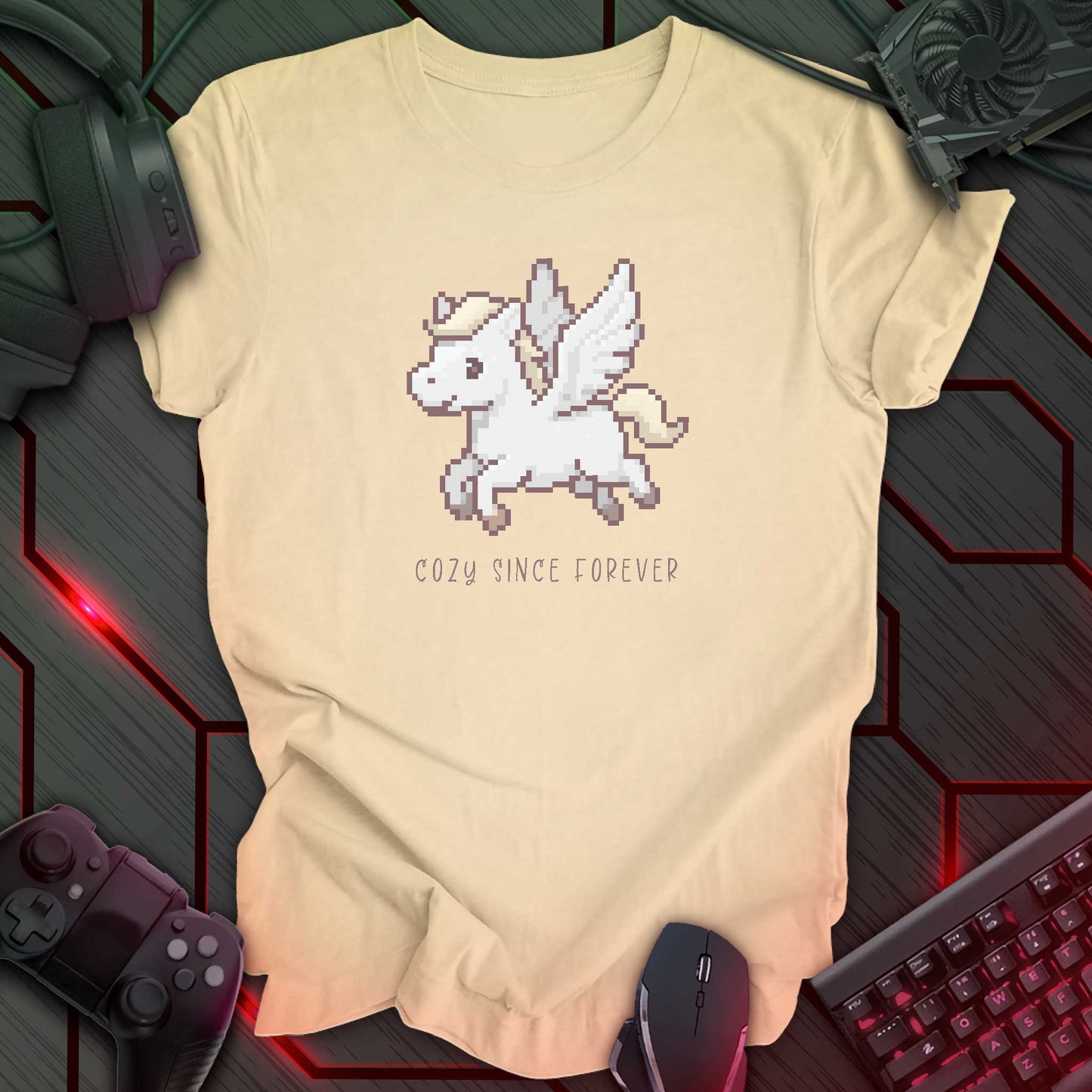 soft cream color t-shirt with a chest print of a pixel art cute winged Pegasus flying about handwritten styled text that reads "COZY SINCE FOREVER".