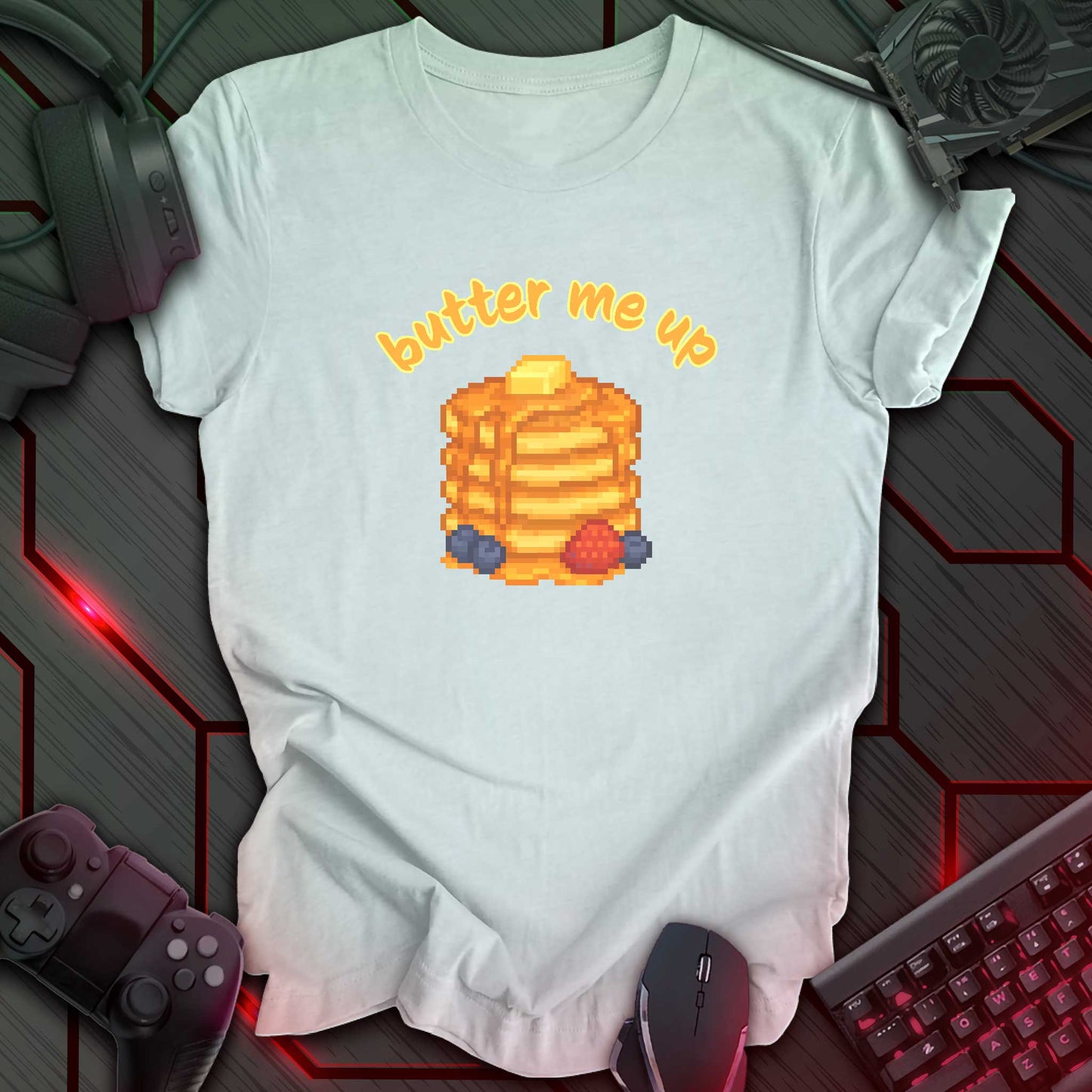 Pixel art stack of pancakes topped with butter and syrup, surrounded by blueberries and a strawberry, with text "butter me up" in kawaii style. Ice Blue Heather background.