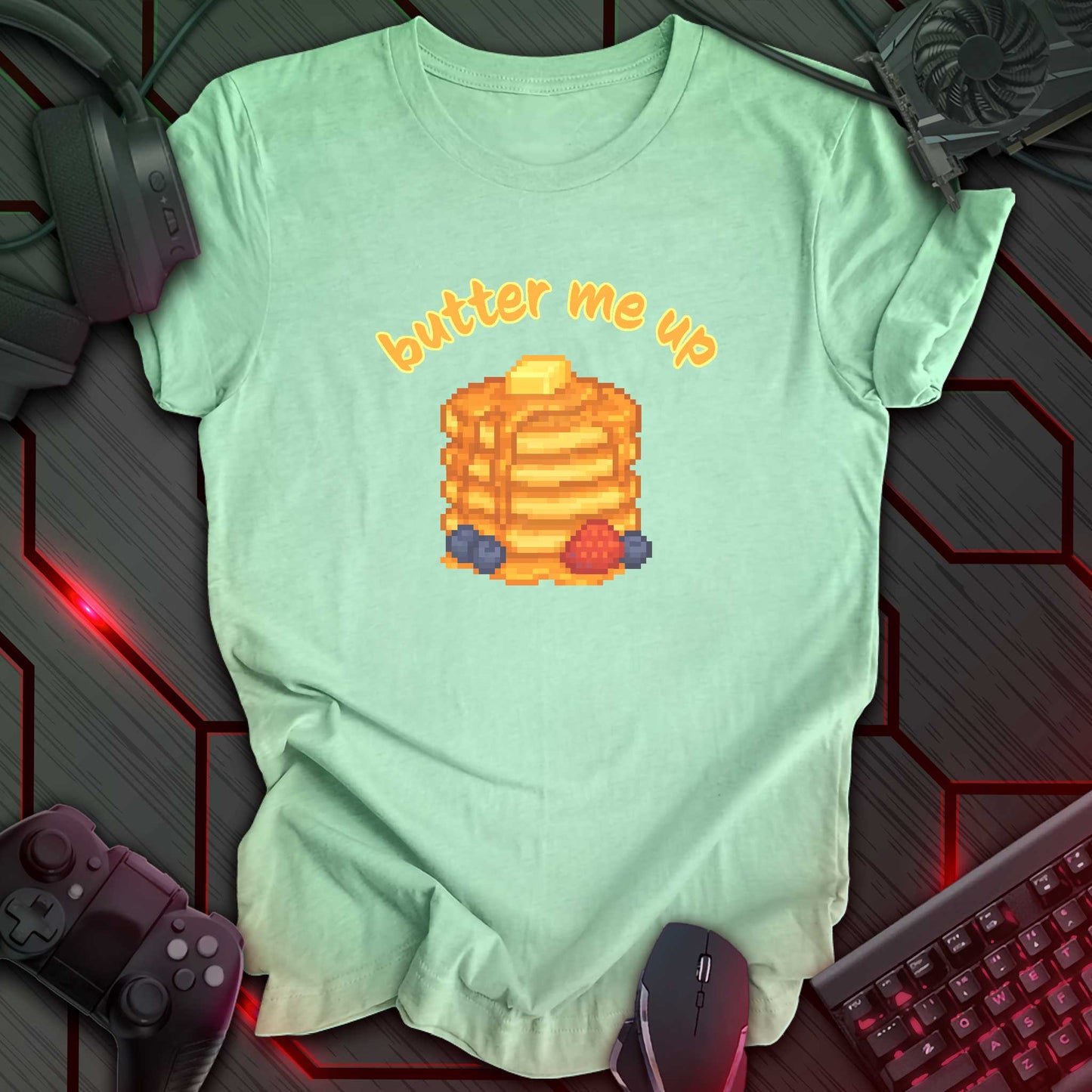 Pixel art stack of pancakes topped with butter and syrup, surrounded by blueberries and a strawberry, with text "butter me up" in kawaii style. Heather Mint background.