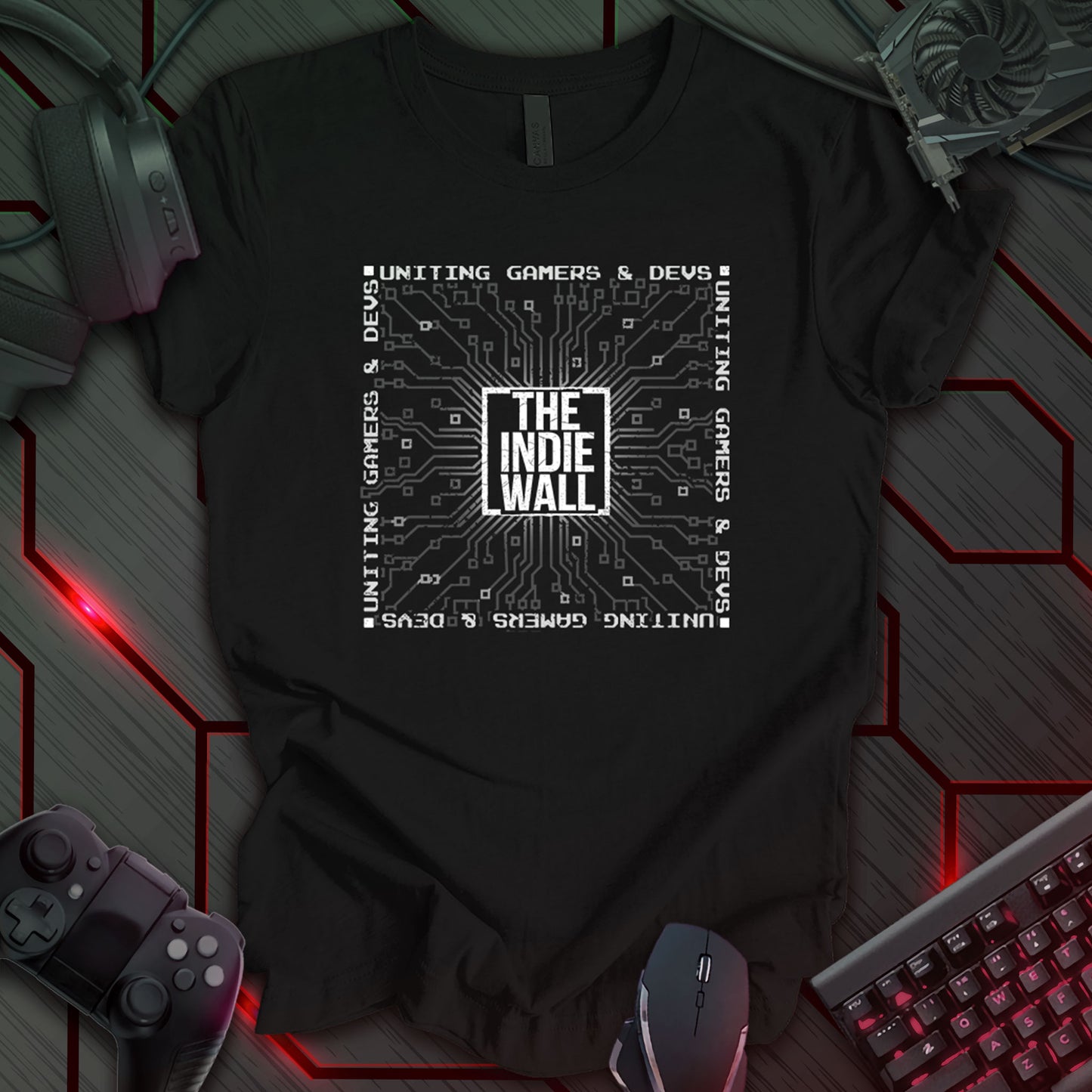 Black gaming t-shirt featuring a distressed black and white design of The Indie Wall logo centered within a graphic circuit board pattern. Surrounding text reads "Uniting Gamers and Devs" in a bold border style.