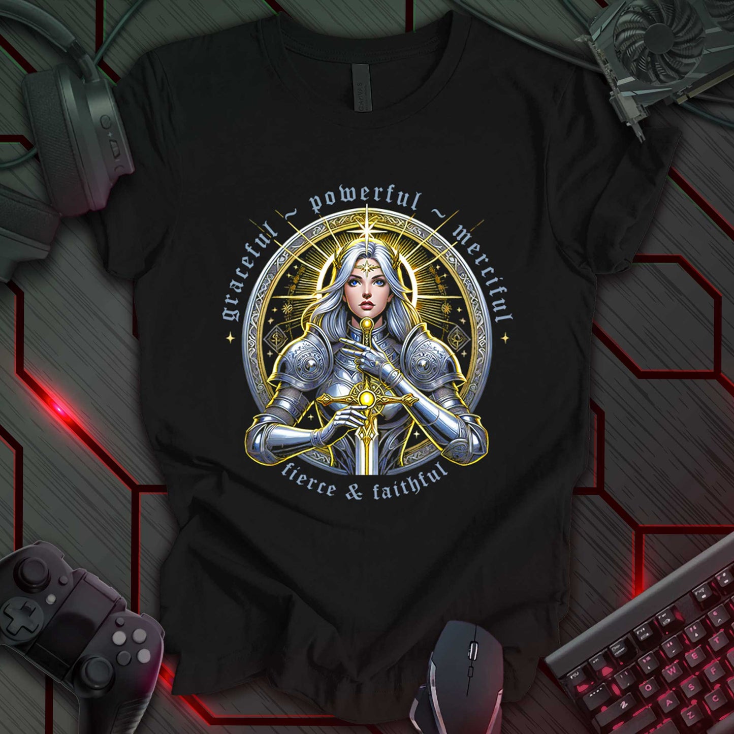 This t-shirt design, created for fans of fantasy art and strong female characters, features a detailed illustration of a female warrior in silver armor, holding a sword, against a circular, ornate golden background. The words 'graceful ~ powerful', 'merciful', and 'fierce & faithful' are arranged around the circle, with 'THE INDIE WALL' in the bottom right corner. This design appeals to those who appreciate powerful imagery and fantasy themes.