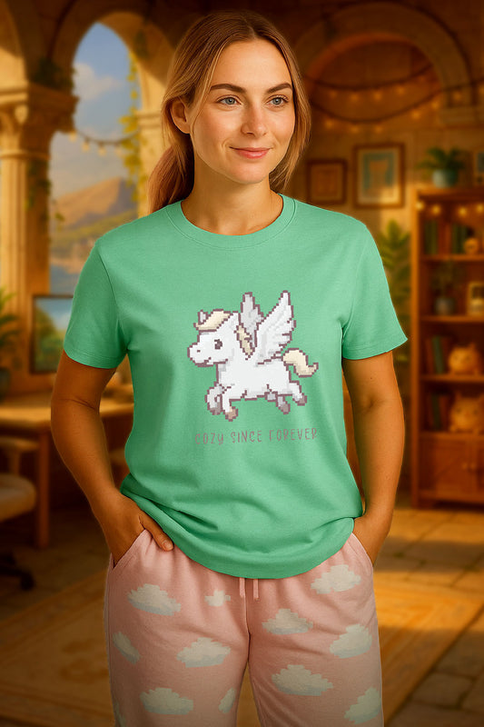 young woman wearing a mint green t-shirt with a chest print of a pixel art cute winged Pegasus flying about handwritten styled  text that reads "COZY SINCE FOREVER". she is standing in an ancient Greece themed cozy room. 