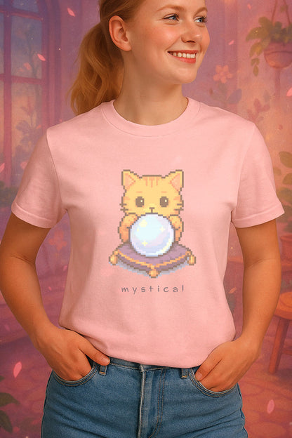 Pixel art orange cat holding glowing crystal ball with “Mystical” text underneath t-shirt design on a light pink t-shirt worn by a young female model. She is standing in front of a soft pastel illustration of a cozy themed room.