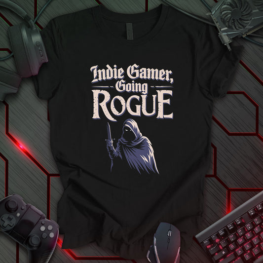 Illustration of a cloaked figure holding a dagger, rendered in shades of gray and beige, against a black background. Above the figure are the words 'Indie Gamer, Going Rogue' in a stylized font. This is a design for indie gamers, featuring a rogue character motif.