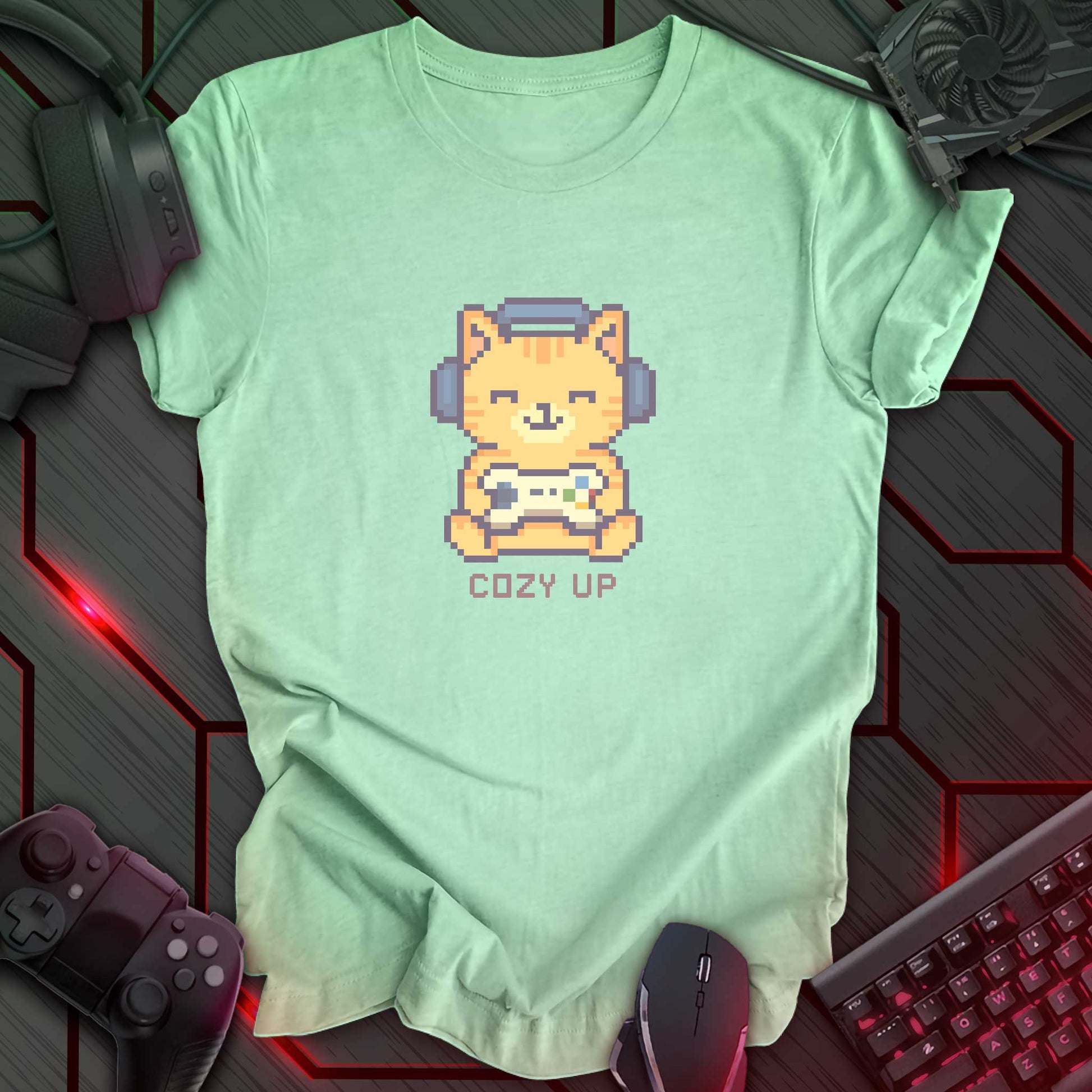 Pixel art orange cat wearing headphones and holding a game controller above the words "Cozy Up" in cozy gamer kawaii style. Heather Mint background.