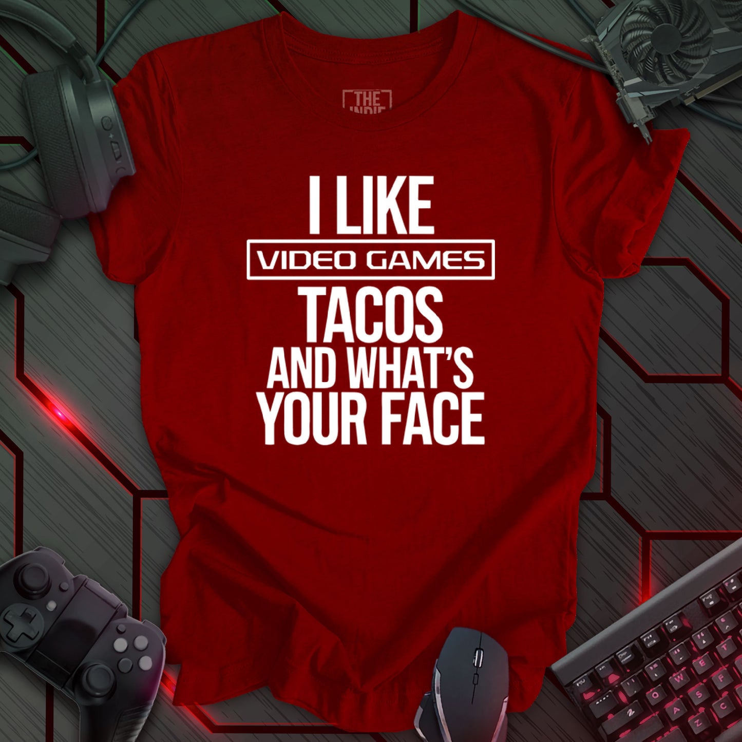 Graphic design featuring the phrase 'I LIKE' in a bold, slightly distressed font at the top, followed by 'VIDEO GAMES' with a rectangle boarder, 'TACOS', and 'AND WHAT'S YOUR FACE' each on separate lines in the same bold, distressed font. All text is white against a cardinal red background. This is a humorous design with an indie gaming and food theme, featuring a playful and quirky sentiment.
