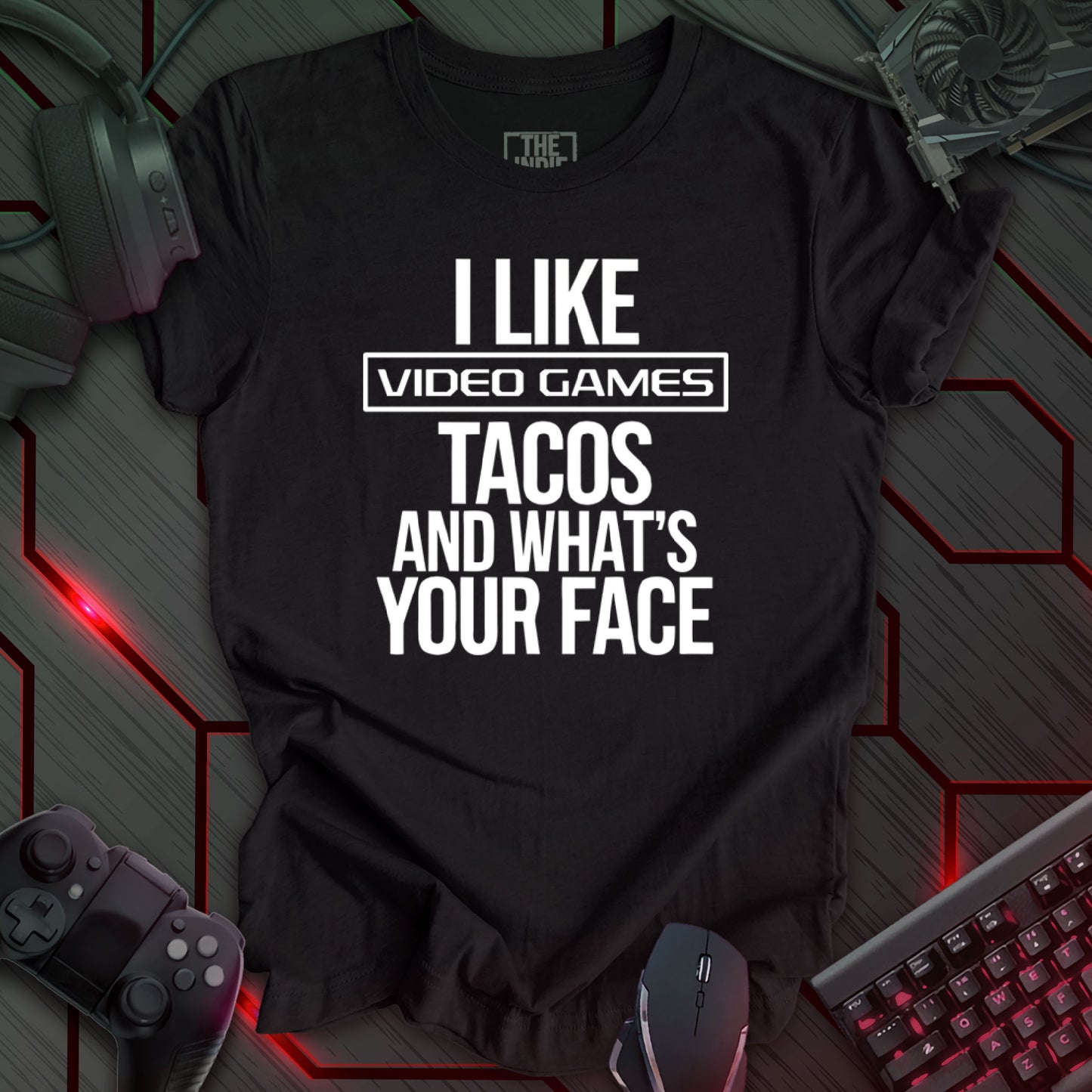 Graphic design featuring the phrase 'I LIKE' in a bold, slightly distressed font at the top, followed by 'VIDEO GAMES' with a rectangle boarder, 'TACOS', and 'AND WHAT'S YOUR FACE' each on separate lines in the same bold, distressed font. All text is white against a heather black background. This is a humorous design with an indie gaming and food theme, featuring a playful and quirky sentiment.
