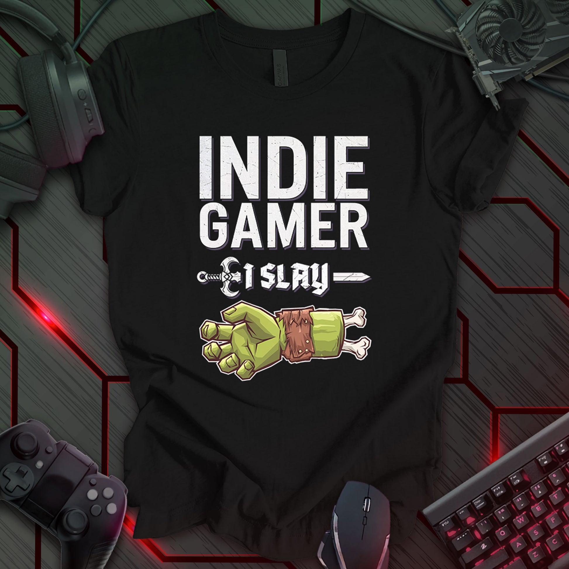 This t-shirt design, created for indie gamers, features the text 'INDIE GAMER' in a bold, distressed font at the top. Below, a pixel art image of a green zombie hand making a 'rock on' gesture is displayed, with the phrase 'I SLAY' between two decorative sword-like lines. This design appeals to gamers who enjoy horror themes and the challenging nature of independent games.