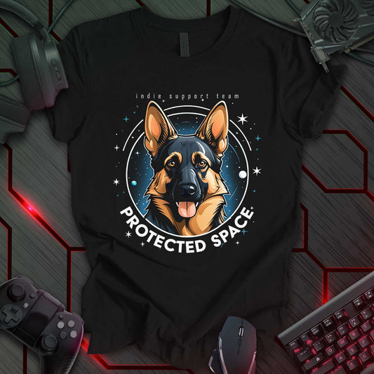 Black t-shirt featuring a German Shepherd portrait set against a cosmic background with stars and planets. Bold text below reads "PROTECTED SPACE," while subtle text above says "indie support team," making it a stylish gift for pet lovers and gaming enthusiasts.